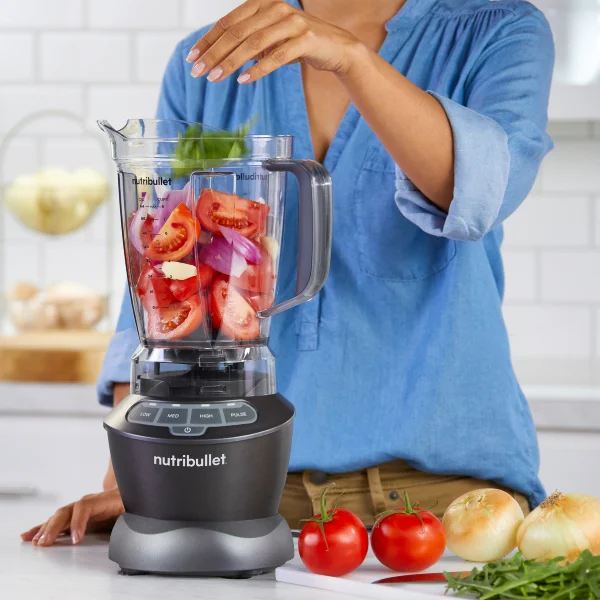 Woman blending tomatoes in nutribullet countertop blender.