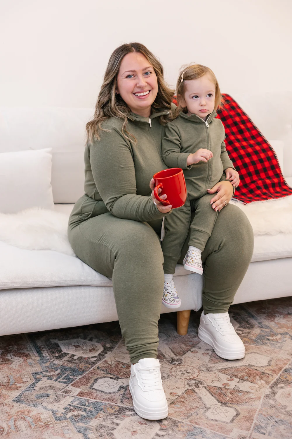 mom and kid wearing green shay romper sat on couch