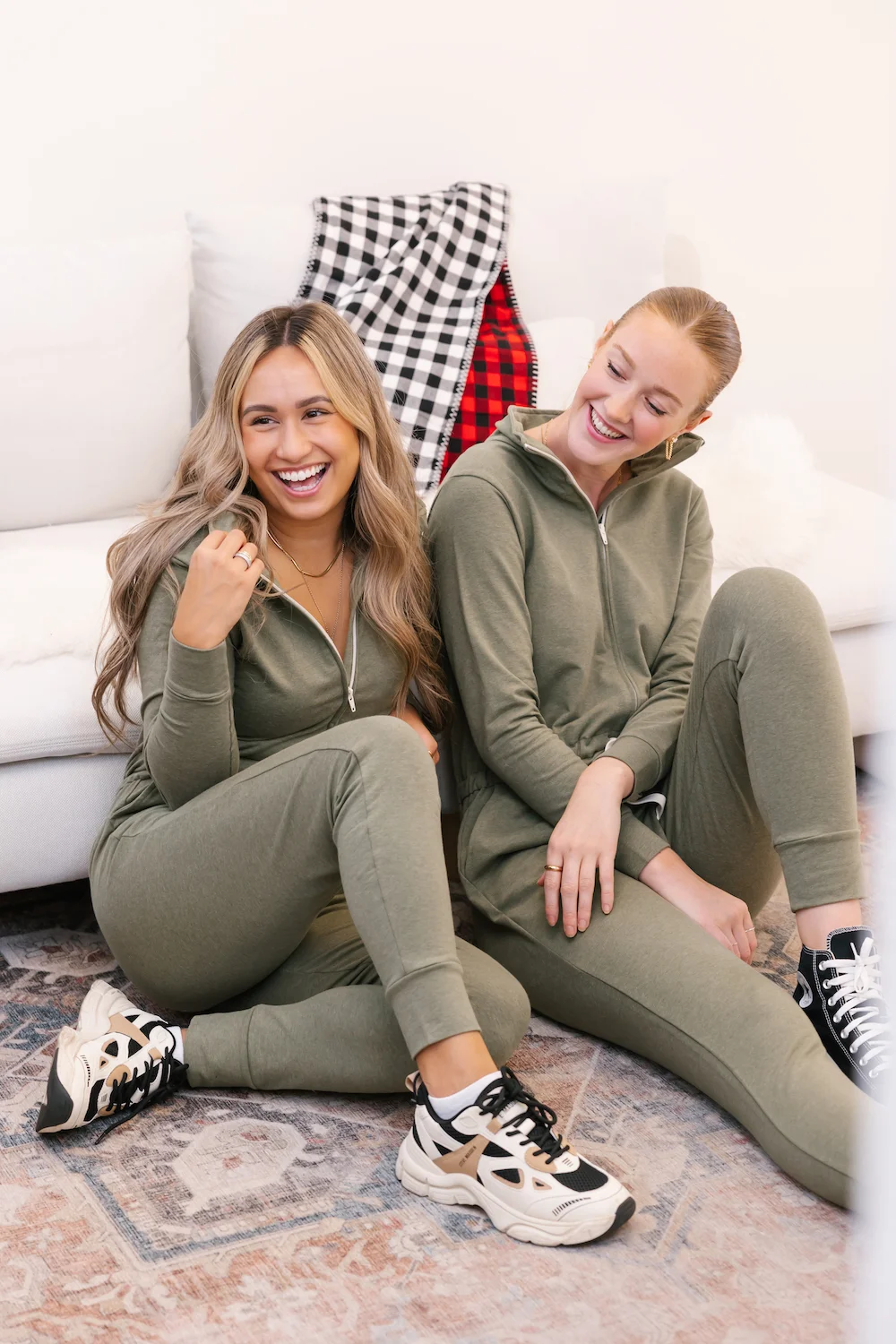 two women wearing green shay romper sat on rug
