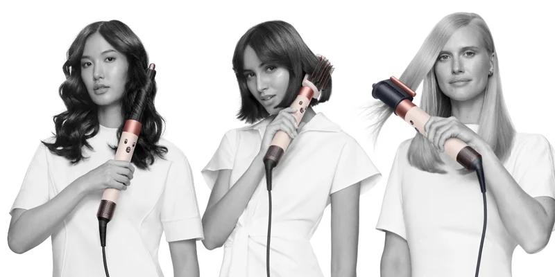 Three models styling their hair with the Dyson Airwrap in Ceramic pink and rose gold