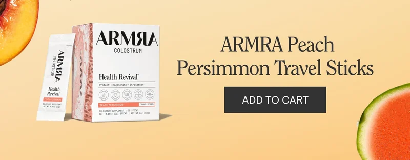 Box and stick packets of ARMRA Colostrum Health Revival Peach Persimmon flavor shown on a peach-colored background with text reading ‘ARMRA Peach Persimmon Travel Sticks’ and an ‘ADD TO CART’ button.