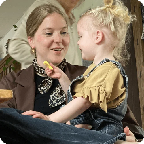 a mom smiling at her toddler daughter, who's sitting on her lap, because she's doing a digital detox for moms a mom smiling at her toddler daughter, who's sitting on her lap, because she's doing a digital detox for moms