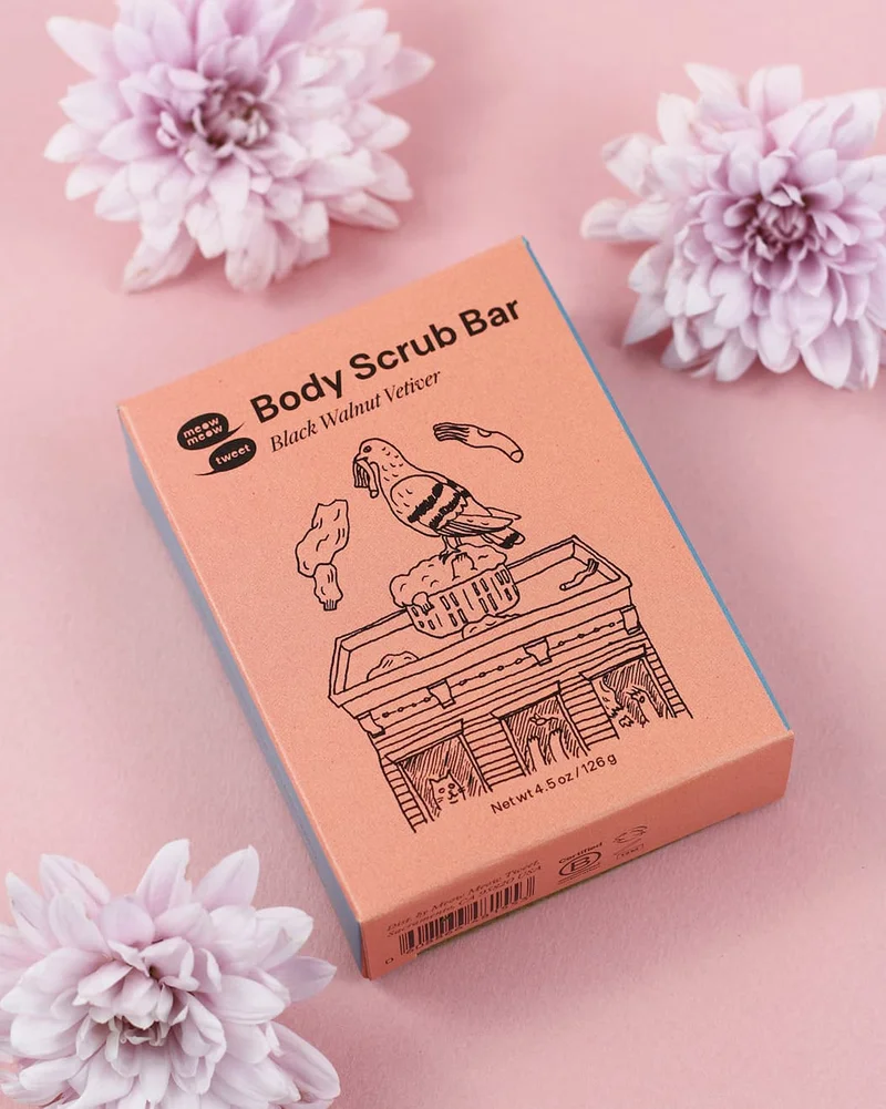 An orange box sits on a pink background with pink dahlias around it