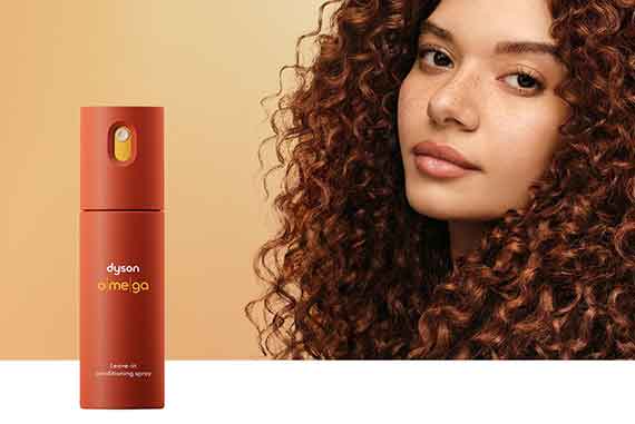 A model with nourished hair behind the Dyson Omega leave-in conditioning spray.