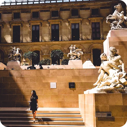 Image Description: A person walking on steps in a courtyard surrounded by statues.