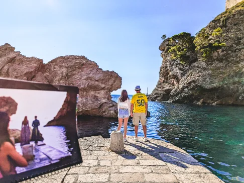 Image Description: Two people posing by the water with cliffs in the background.