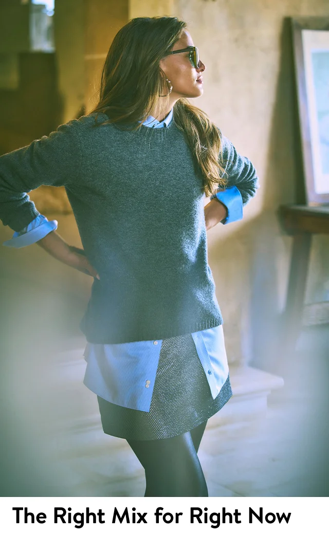 A woman wearing a sweater with a button-front shirt and a skirt.