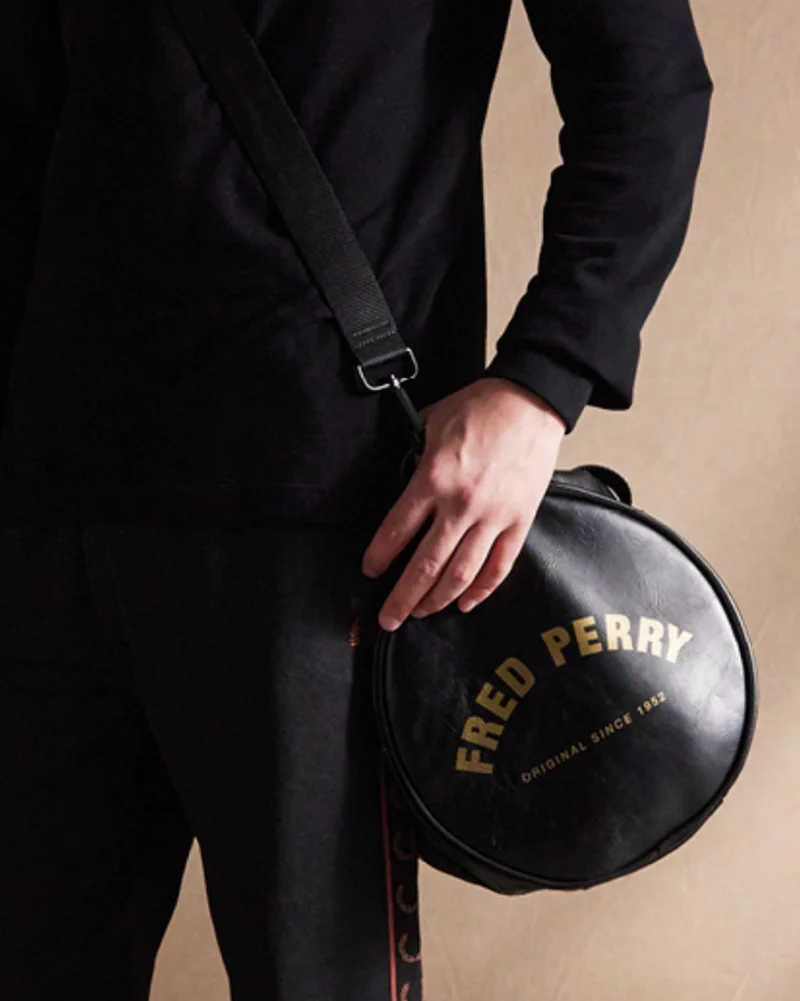 Black and whisky brown tracksuit trousers with black and gold barrel bag