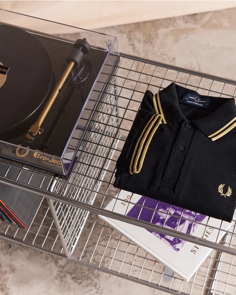 Black and gold Fred Perry Shirt with matching Pro-Ject record player