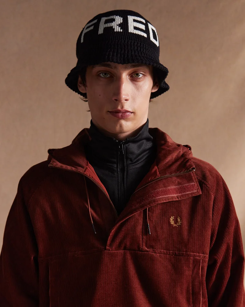 Whisky brown corduroy half-zip coat with big front pocket and a knitted black & white bucket hat