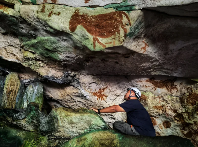Shinatria Adhityatama examines cave art in one of the caves of Sulawesi, Indonesia.