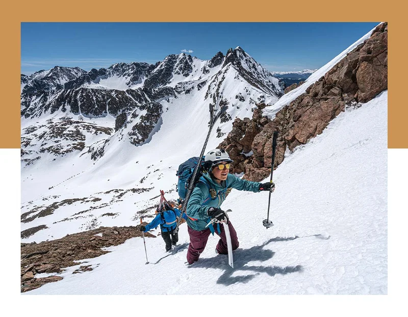 Two people climbing up a snowy mountain.