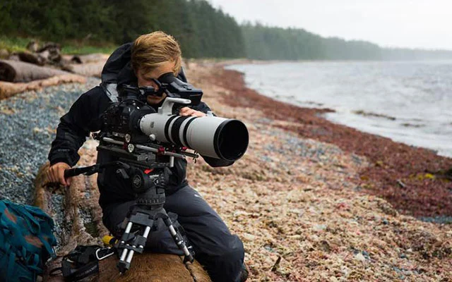 Bertie Gregory holding a camera trying to get the perfect shot.