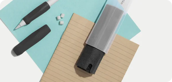The cleaning kit on top of a notebook, and next to an Apple Pencil with Paperlike's charcoal grips.
