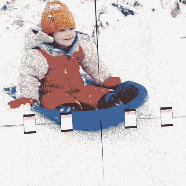 A grainy film image of a happy child sledding on the snow.