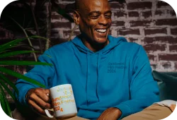 Model wearing blue festival branded hoodie and holding an SFF24 branded mug.