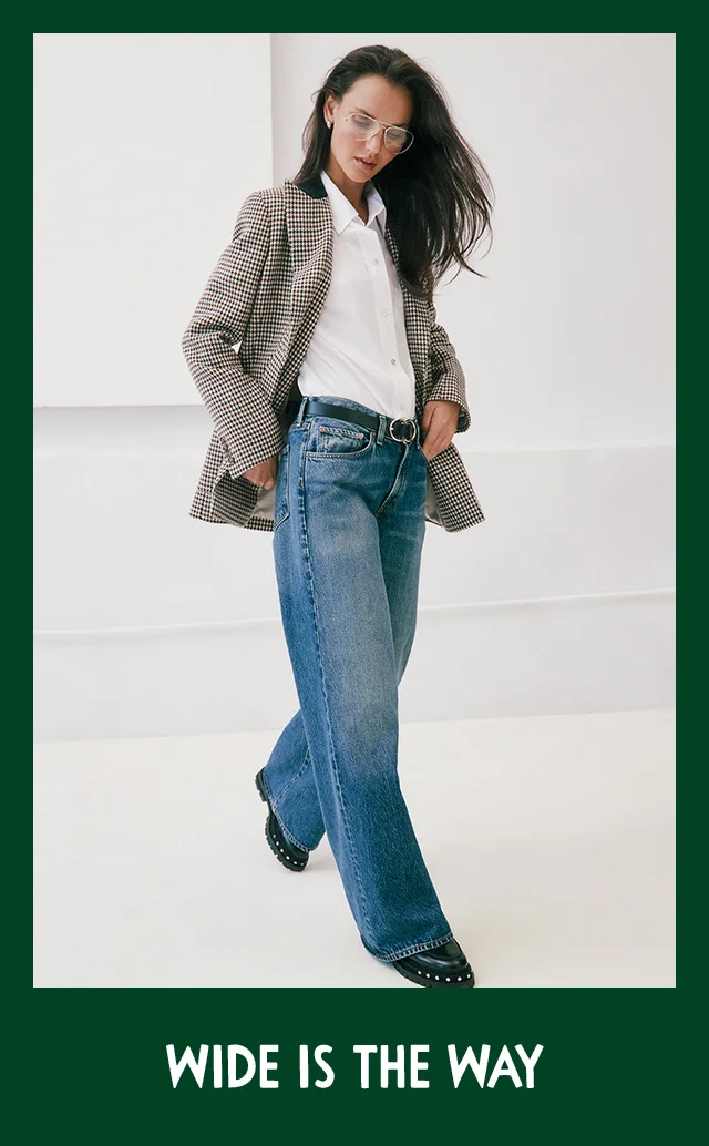 A woman wearing wide-leg jeans with a white button-front shirt, plaid blazer and black boots.