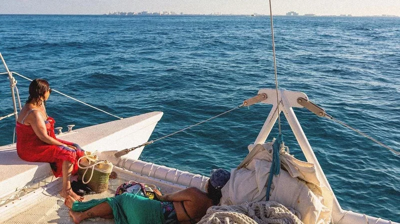 Image description: Two young women on a boat looking out over Cancun’s skyline.