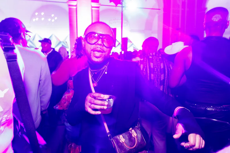 A person on a dance floor holding a drink with purple light around them