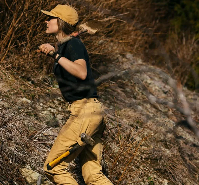 Patagonia. A person climbs a steep hillside with a shovel...