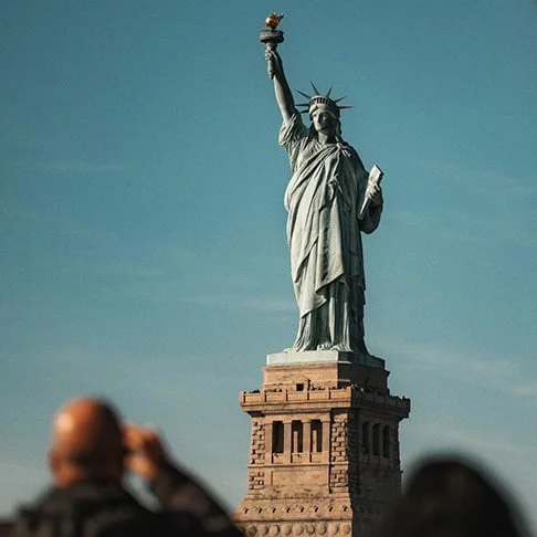 Image Description: A traveler snapping a photograph of the Statue of Liberty