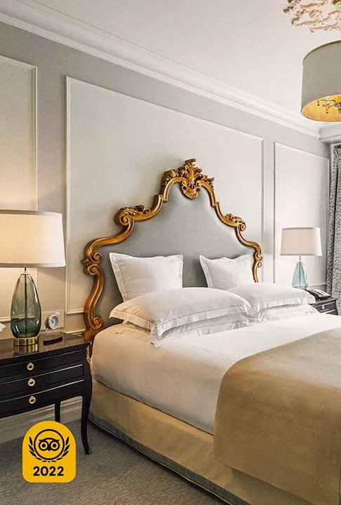 Image Description: A stylish hotel suite featuring an overhead light and a large bed with a gold headboard