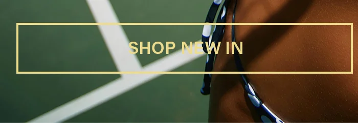 Person in a blue polka-dot bikini bottom on a green tennis court. Discover new arrivals and latest swimwear fashion. Shop New In!