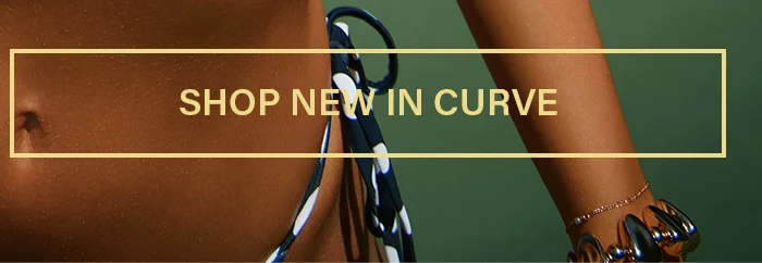 Torso and arm of a model in a black polka dot bikini top, accented with gold jewelry. Shop new arrivals in the curve collection now.