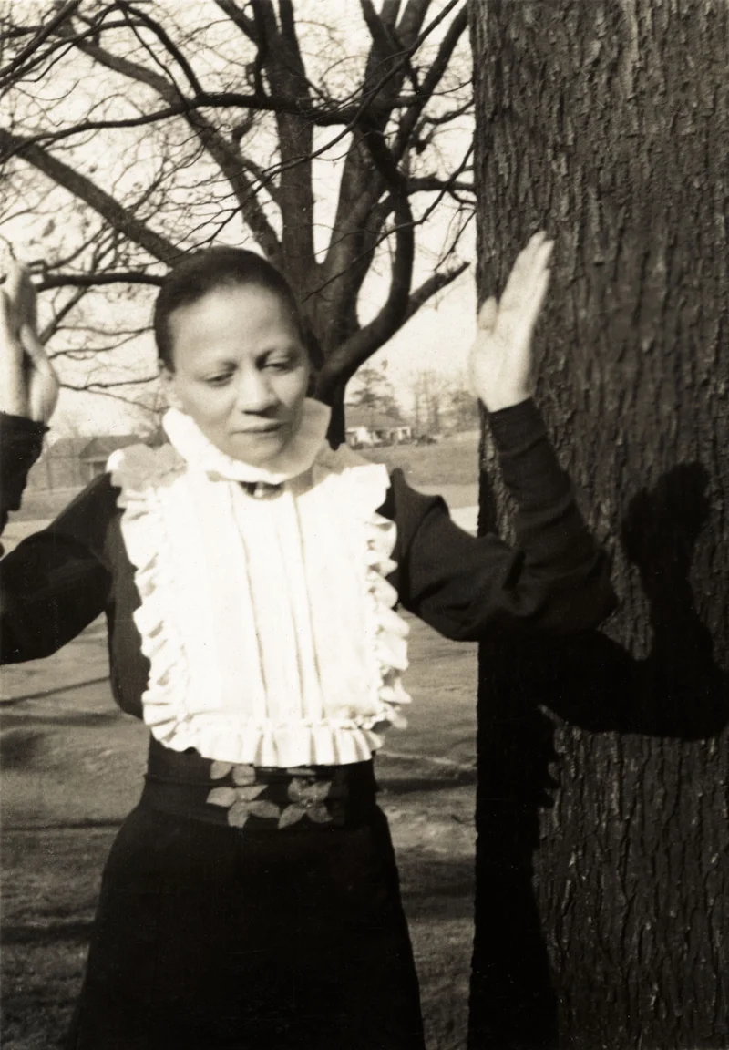 Black-and-white photograph of a woman raising her hands