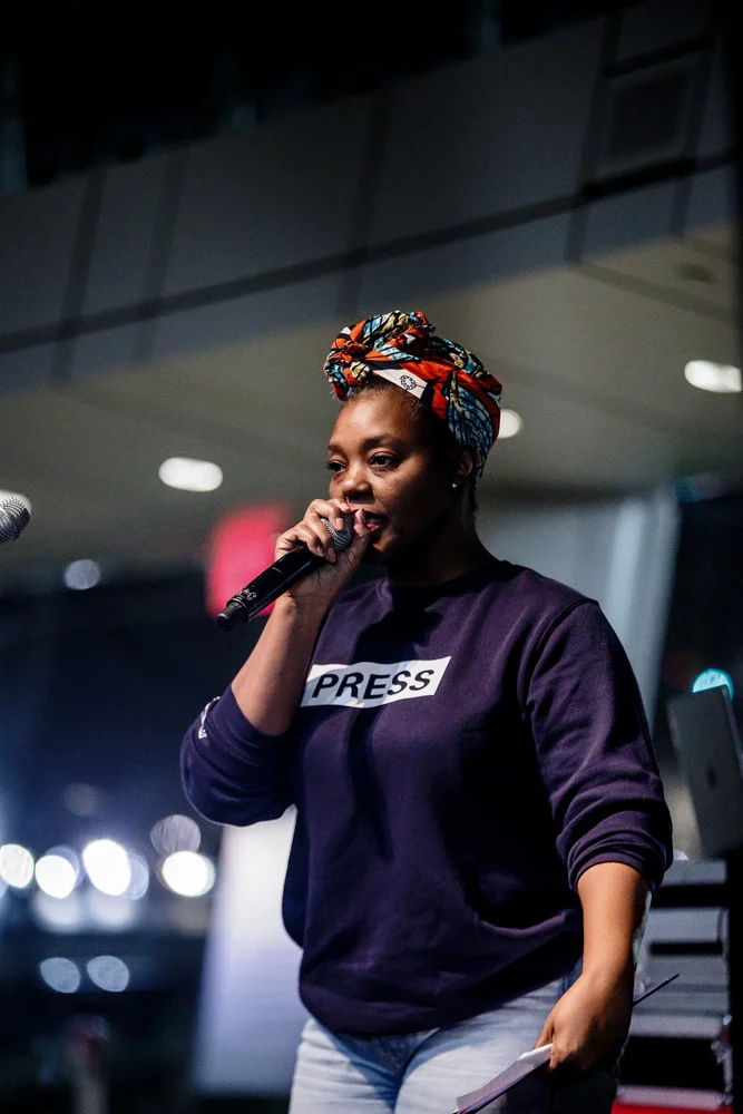 Mahogany L. Browne holds a microphone on a stage