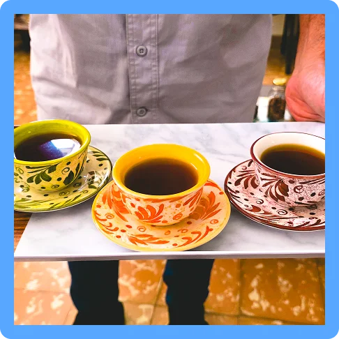 Image description: Three cups of coffee in colorful mugs on a platter