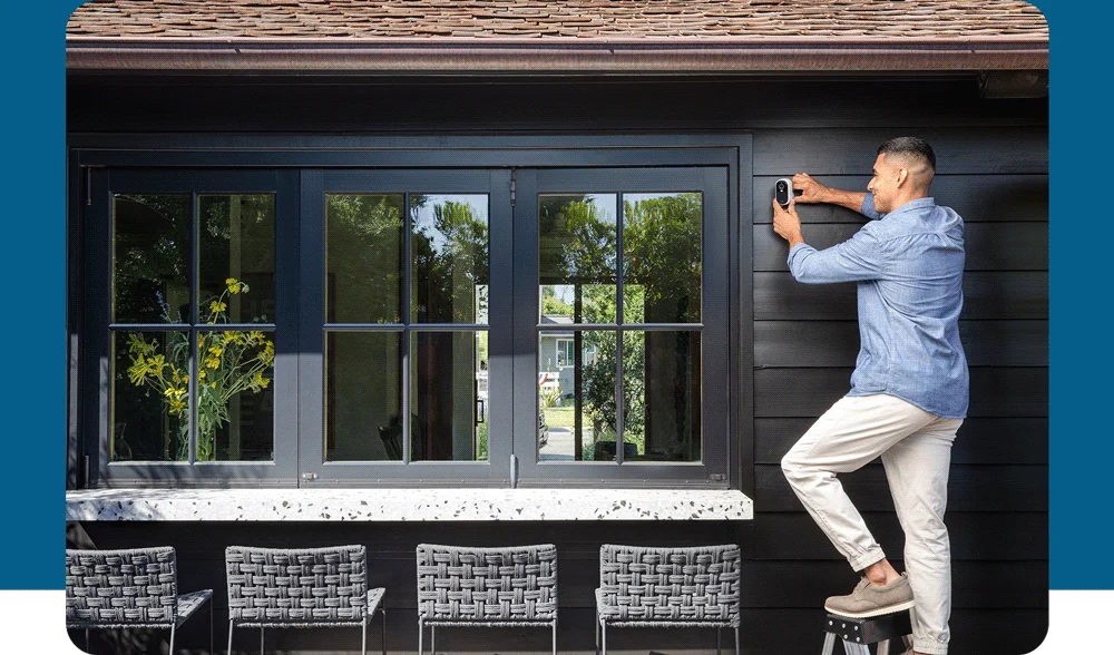 Person installing an Arlo Essential Wireless Security Camera on the exterior of a house.