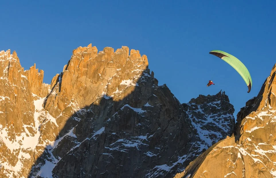 A climber high on a big wall reaches to place a piece of protection.