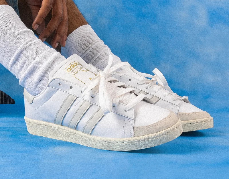 Person wearing Jabbar shoe in white with off-white stripes on blue background.