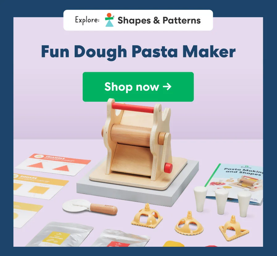 A wooden pasta maker toy with colorful playdough pasta strands neatly rolled out, accompanied by various pretend-play kitchen items.