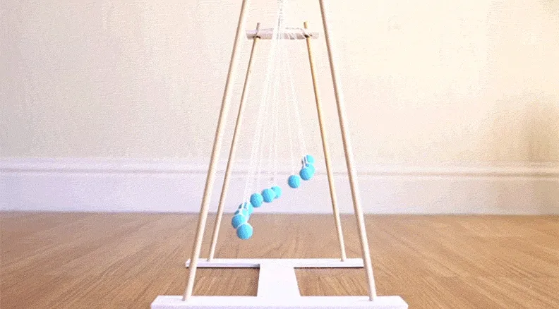 A wooden pendulum wave project in motion, with several pendulums swinging in synchronized patterns, creating mesmerizing wave-like motions.