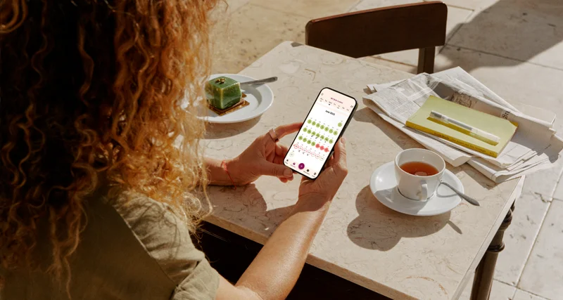 Person wearing Oura Ring looking at Natural Cycles app on phone