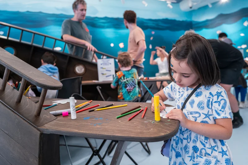 A child drawing with colored pencils in an ocean-themed space