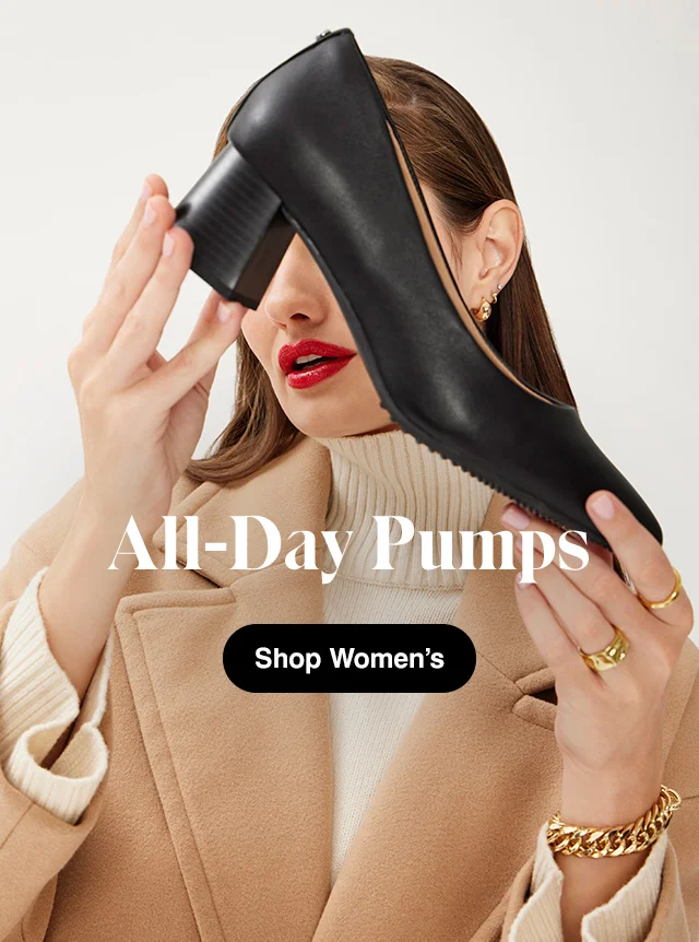 Woman in tan coat holding the black leather Glory pump with block heel. Shop Women’s Shoes