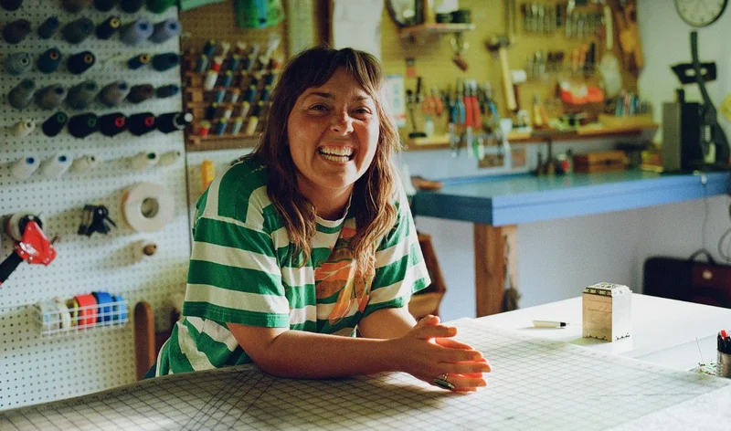 A person smiles in their sewing workshop.