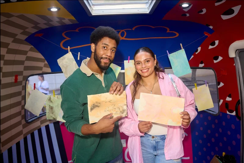 Two people holding works on paper