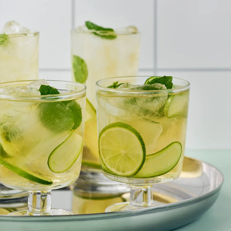 Glass of lemonade with limes and mint inside.