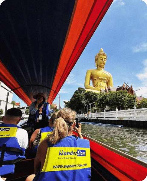 Image Description: Travelers taking photos of a giant Buddha statue during a canal cruise in Bangkok