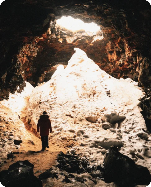 Image Description: A lone traveler exploring the Raufarholshellir lava tunnel in Iceland