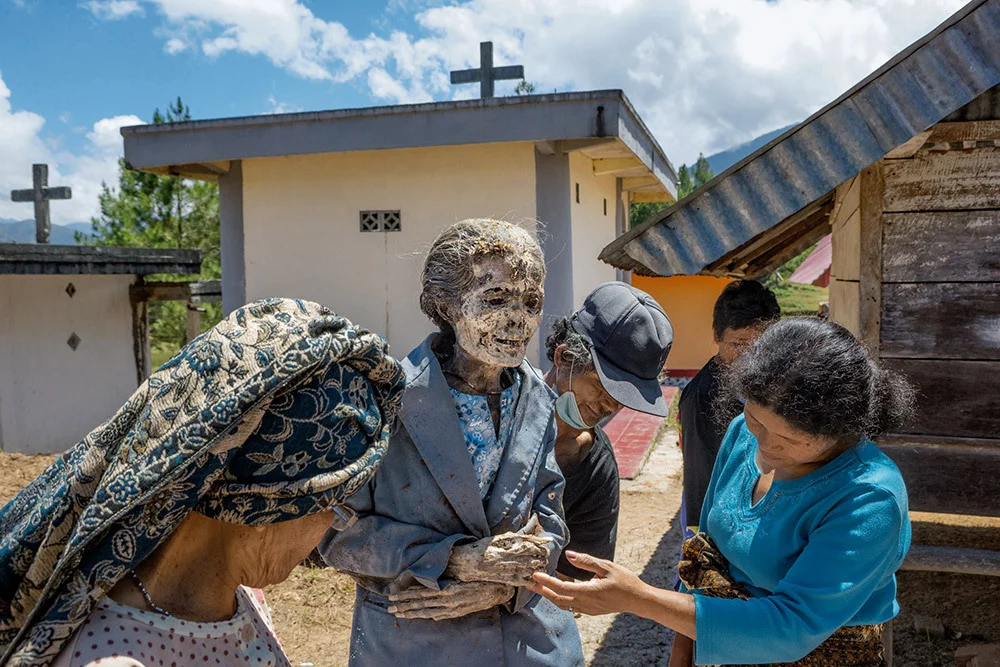 Friends and family inspect the body of Debora Maupa’, who died in 2009 at age 73. A well-preserved body, mummified with a solution of formaldehyde and water, is thought to bring good fortune.