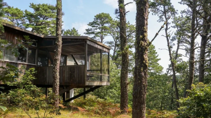 Marcel Breuer’s Wellfeet cottage with a cantilever screened porch surrounded by trees.